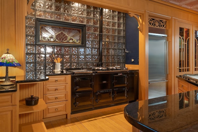 bar featuring dark stone countertops, light wood-type flooring, and high end fridge