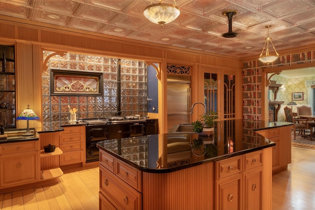 kitchen with sink, light wood-type flooring, decorative light fixtures, and a center island