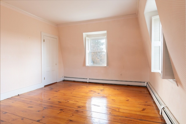 empty room featuring a baseboard heating unit, light hardwood / wood-style floors, and ornamental molding