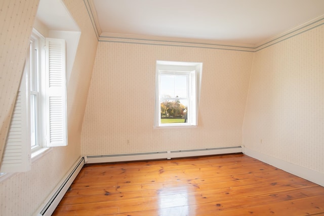 empty room with baseboard heating, light hardwood / wood-style floors, and crown molding