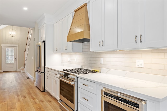 276 Sterling Dr, Laconia, NH 03246 - kitchen with appliances with stainless steel finishes, a chandelier, tasteful backsplash, custom exhaust hood, and white cabinetry