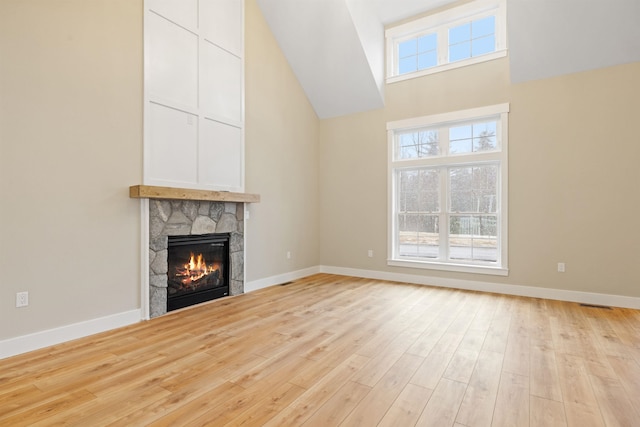 276 Sterling Dr, Laconia, NH 03246 - unfurnished living room featuring light wood-type flooring, a fireplace, a towering ceiling, and baseboards