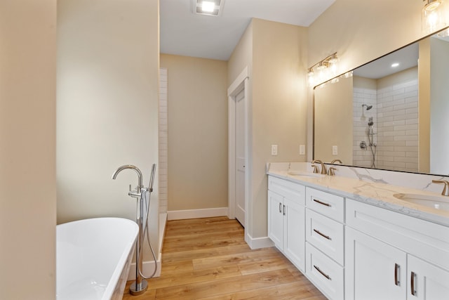 276 Sterling Dr, Laconia, NH 03246 - full bathroom featuring wood finished floors, a freestanding bath, double vanity, tiled shower, and baseboards