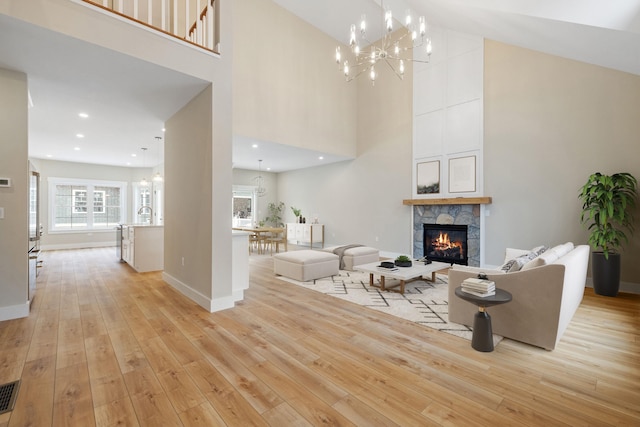 276 Sterling Dr, Laconia, NH 03246 - living area featuring a chandelier, a high ceiling, a stone fireplace, light wood-type flooring, and baseboards
