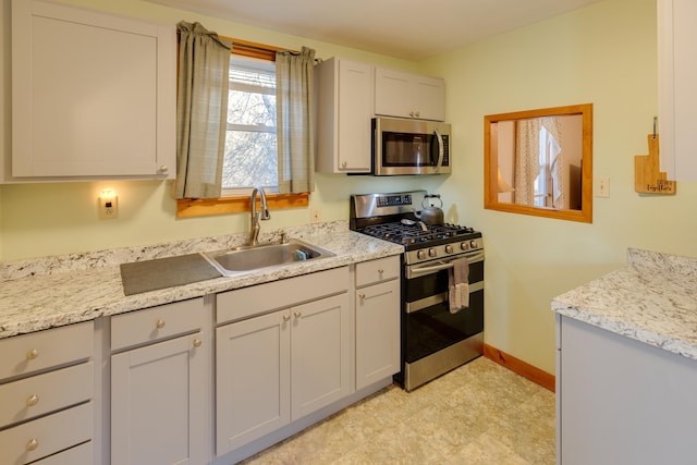 kitchen featuring baseboards, stainless steel appliances, and a sink