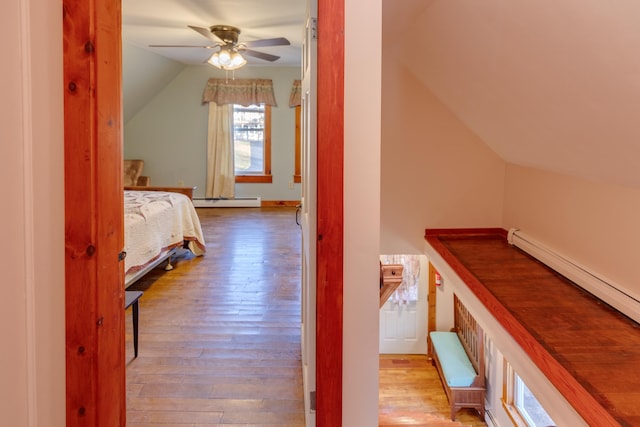bedroom featuring a baseboard heating unit, wood-type flooring, and lofted ceiling
