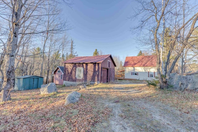 view of front of property with an outdoor structure, a garage, a shed, and metal roof