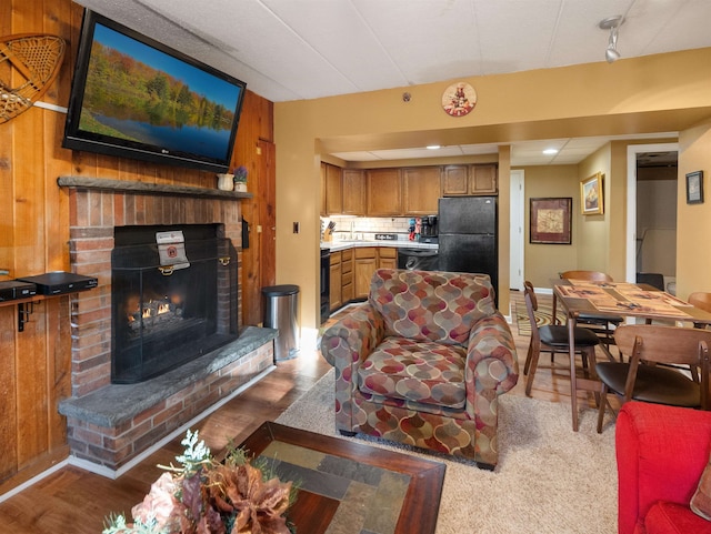 living room with wood walls, wood-type flooring, and a fireplace