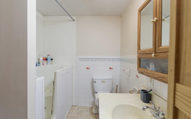 bathroom with sink, tile patterned floors, toilet, and tile walls