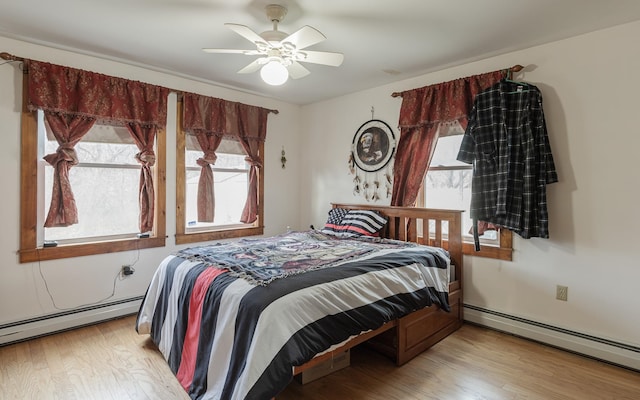 bedroom featuring a baseboard heating unit, ceiling fan, and light hardwood / wood-style flooring