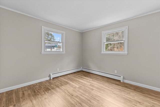 spare room featuring ornamental molding, baseboard heating, and light wood-type flooring