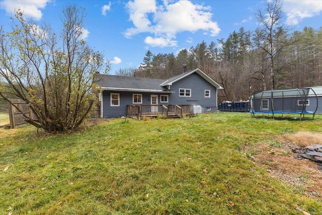 back of house with a lawn, a wooden deck, and a trampoline