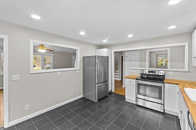 kitchen with white cabinetry, appliances with stainless steel finishes, dark tile patterned flooring, ceiling fan, and butcher block countertops