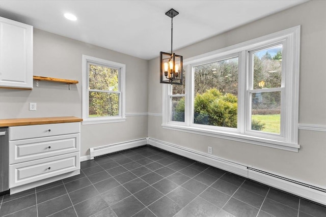 unfurnished dining area with dark tile patterned floors, an inviting chandelier, baseboard heating, and a healthy amount of sunlight