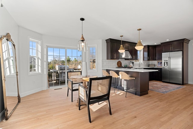 kitchen featuring high quality fridge, dark brown cabinetry, pendant lighting, and light hardwood / wood-style floors