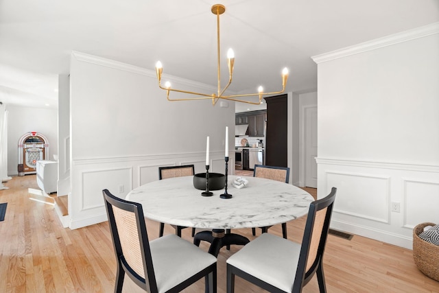 dining area featuring ornamental molding, a notable chandelier, and light wood-type flooring