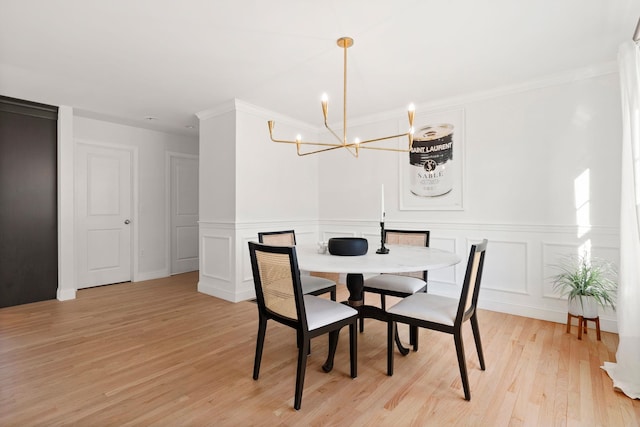 dining room with ornamental molding, light hardwood / wood-style flooring, and a notable chandelier