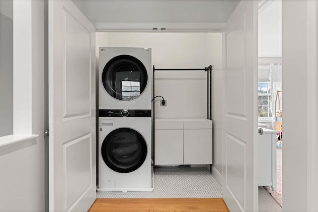 laundry room with stacked washer / drying machine and light wood-type flooring