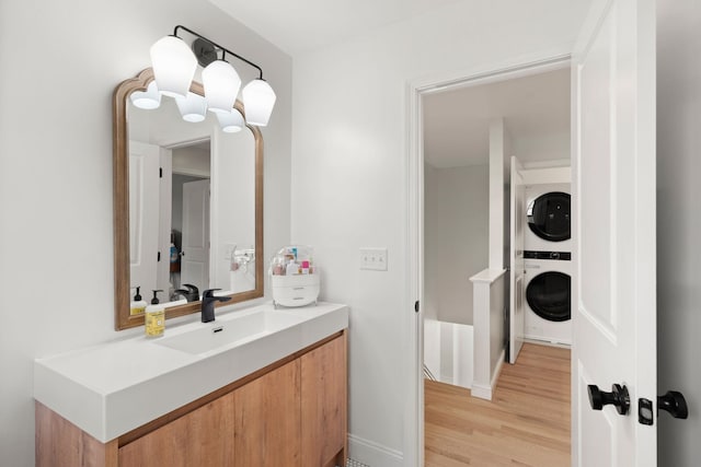 bathroom featuring wood-type flooring, vanity, and stacked washing maching and dryer