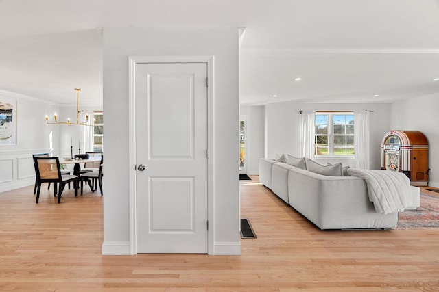 living room featuring an inviting chandelier, light hardwood / wood-style flooring, and ornamental molding