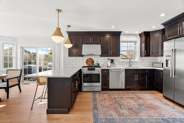 kitchen featuring kitchen peninsula, a wealth of natural light, stainless steel appliances, and range hood