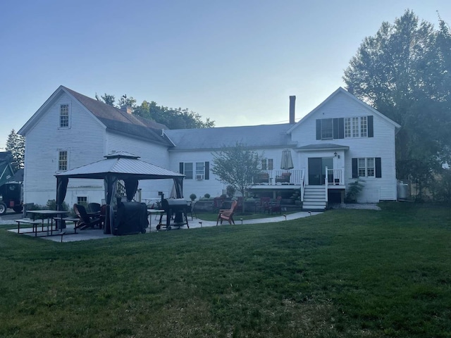 rear view of house featuring a gazebo and a yard