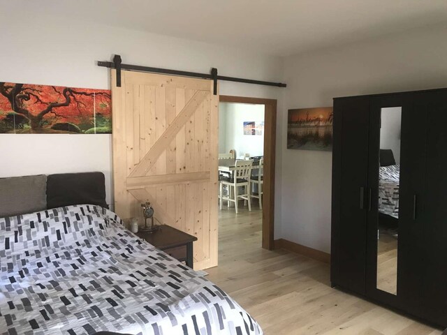 bedroom featuring a barn door and light wood-type flooring