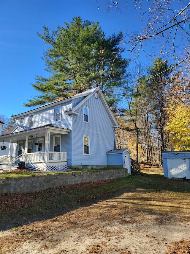 view of property exterior with a lawn, covered porch, and a storage unit