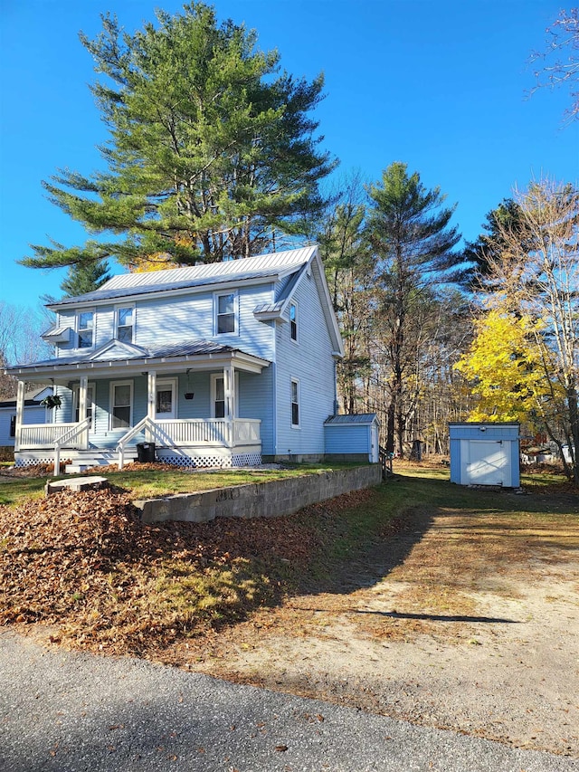 view of front facade featuring a porch and a storage shed