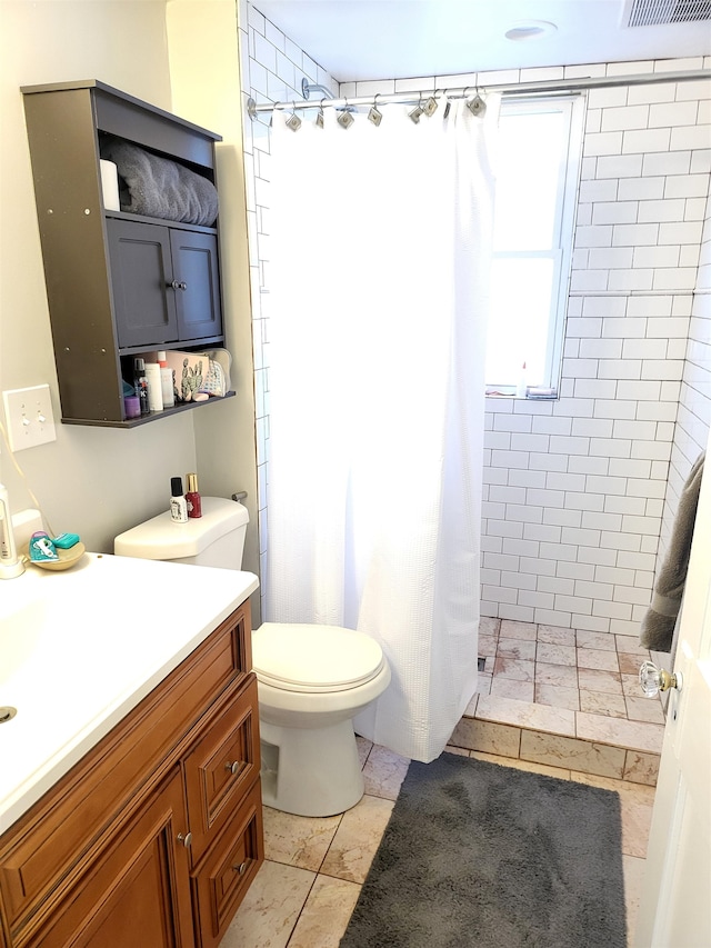 bathroom featuring tile patterned flooring, vanity, toilet, and curtained shower