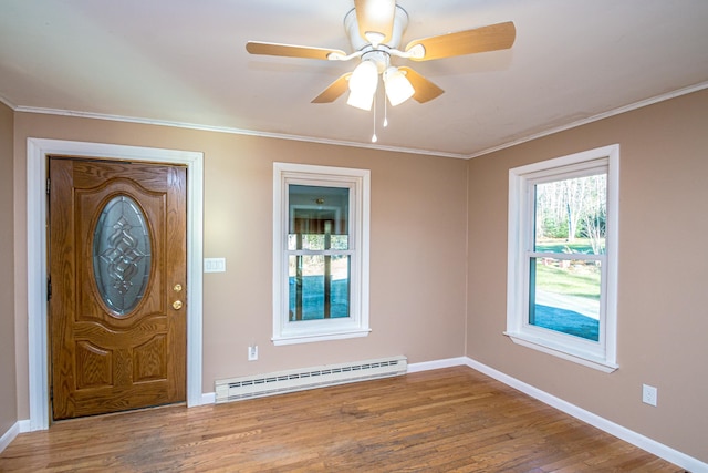 foyer entrance with ceiling fan, ornamental molding, wood-type flooring, and a baseboard heating unit