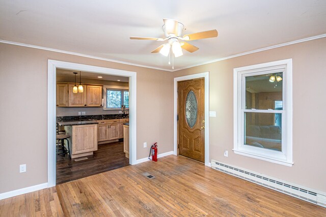 foyer featuring ceiling fan, dark hardwood / wood-style flooring, ornamental molding, and a baseboard heating unit