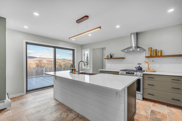 kitchen with a center island with sink, sink, hanging light fixtures, stainless steel gas range, and wall chimney exhaust hood