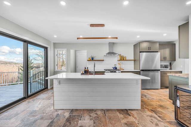 kitchen featuring a center island with sink, wall chimney exhaust hood, sink, and appliances with stainless steel finishes