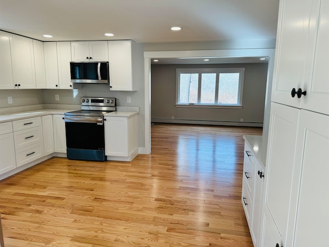 kitchen with white cabinetry, baseboard heating, appliances with stainless steel finishes, and light hardwood / wood-style flooring