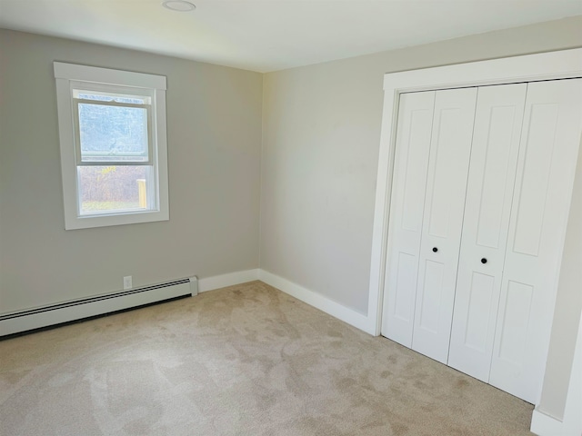 unfurnished bedroom featuring baseboard heating, light carpet, and a closet