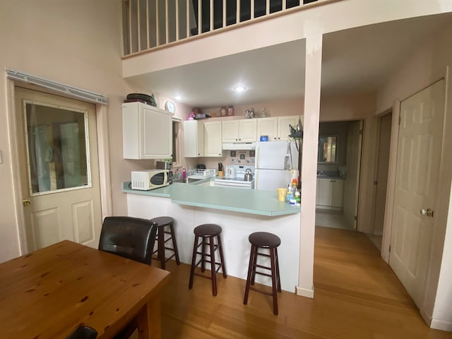 kitchen with white cabinetry, light wood-type flooring, and white appliances