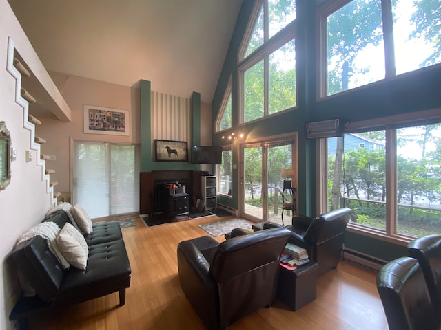 living room with a wood stove, hardwood / wood-style floors, high vaulted ceiling, and a healthy amount of sunlight