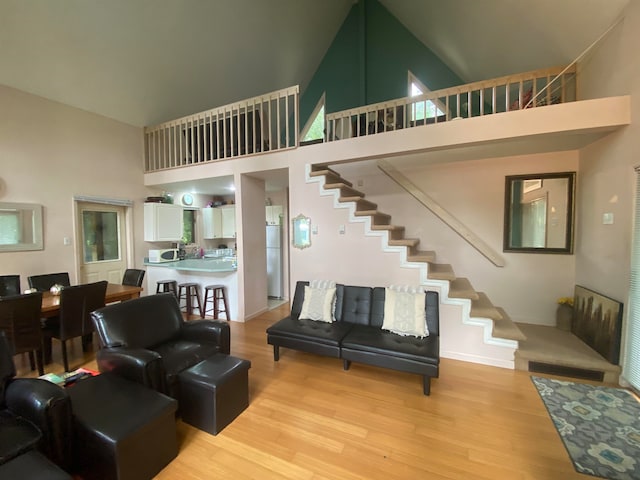 living room with light hardwood / wood-style floors and high vaulted ceiling