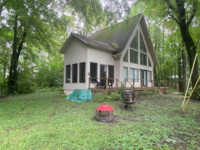 rear view of house featuring a yard, a deck, and an outdoor fire pit