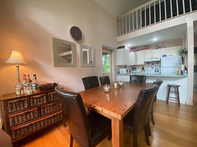 dining room with a towering ceiling and light wood-type flooring