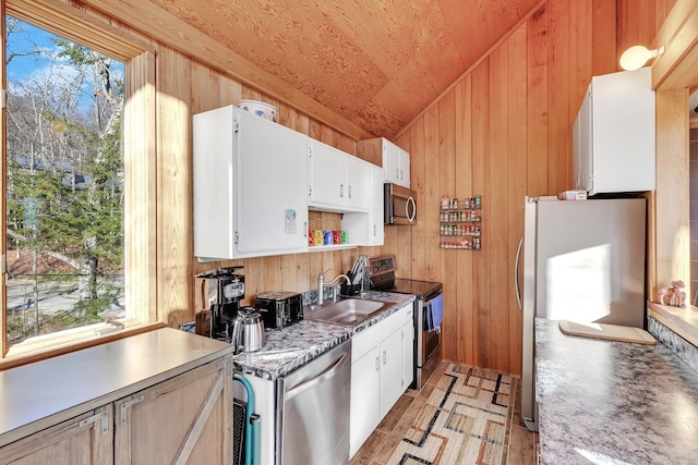 kitchen featuring white cabinets, plenty of natural light, appliances with stainless steel finishes, and vaulted ceiling