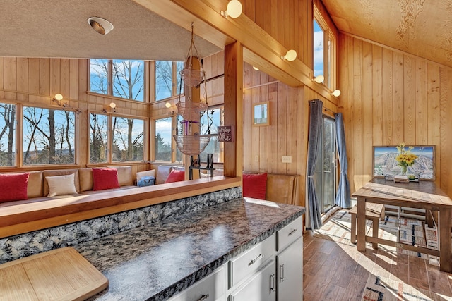 kitchen with white cabinets, dark hardwood / wood-style flooring, wooden walls, and dark stone counters