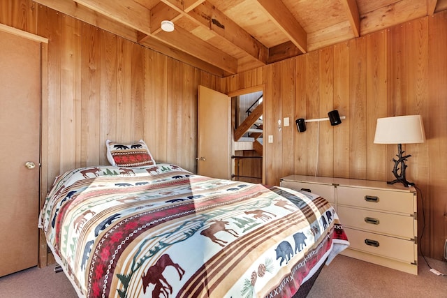 carpeted bedroom with beam ceiling, wooden walls, and wooden ceiling