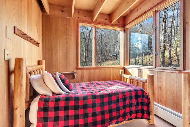 bedroom with baseboard heating, wooden walls, carpet flooring, and beamed ceiling