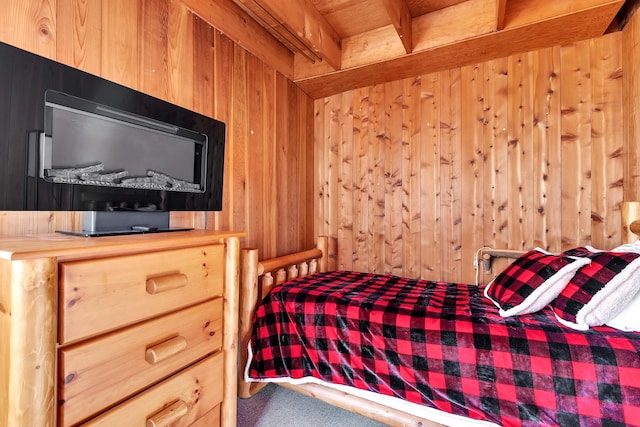 bedroom featuring beam ceiling, wood walls, and carpet