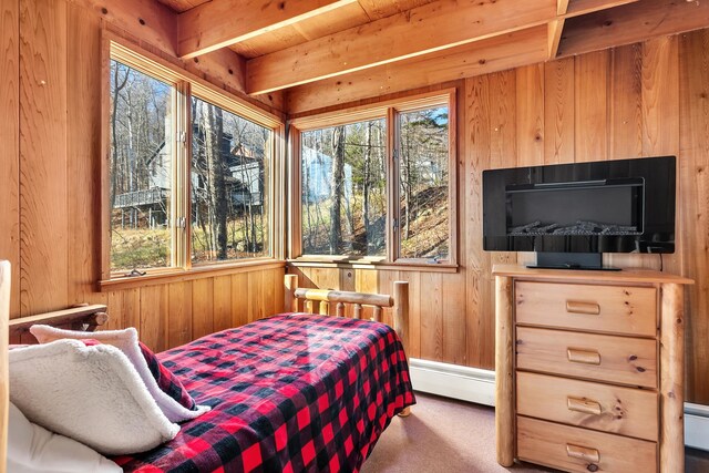 bedroom with carpet flooring, beam ceiling, wooden walls, and a baseboard heating unit