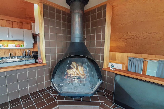 room details with sink, a wood stove, black range oven, and wood walls