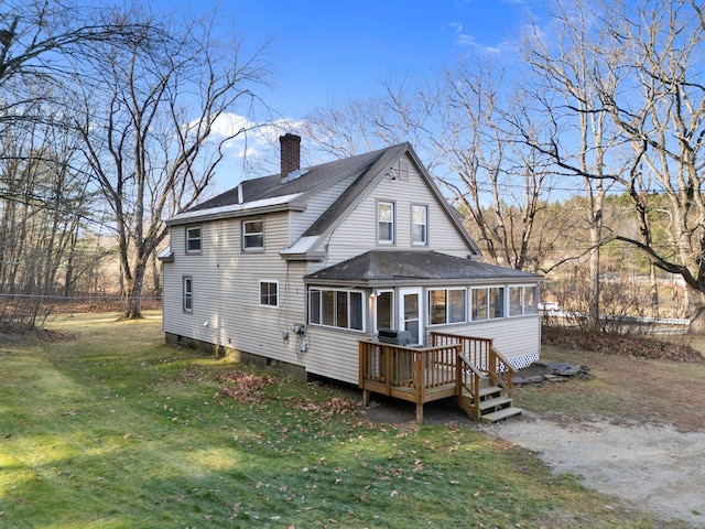 back of house with a deck, a sunroom, and a lawn