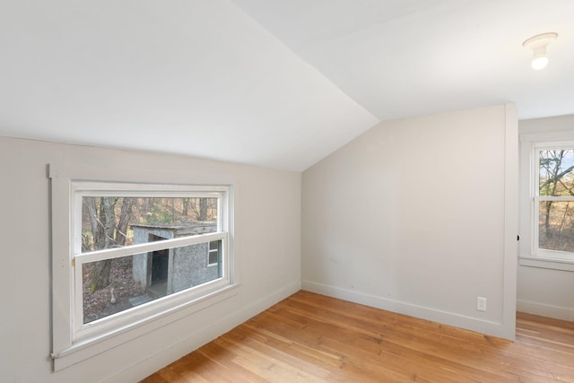 additional living space with light wood-type flooring and vaulted ceiling